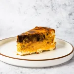 a slice of halloween vanilla bean cheesecake laying on a textured plate.