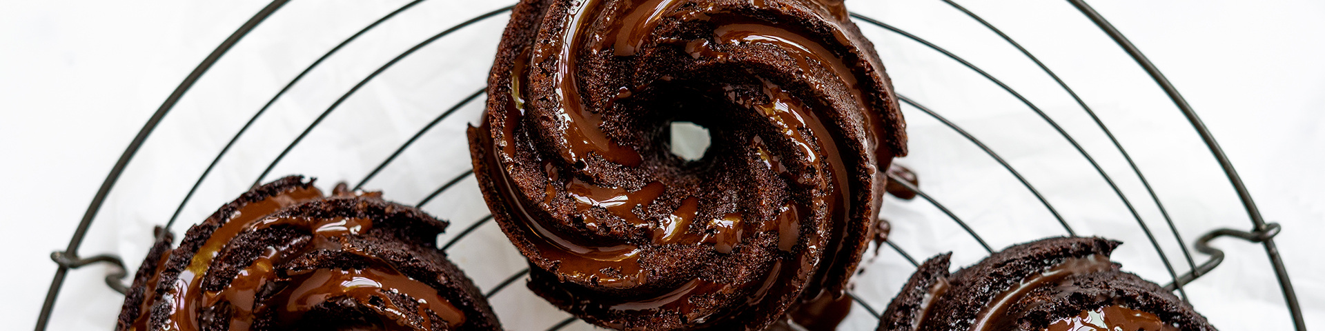 Finished product of the chocolate bundlettes with glaze shown from overhead angle with bowl of espresso glaze and spoon on marble counter