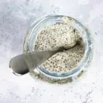 Top view shot of a large jar containing healthy chia seed pudding and a silver spoon.