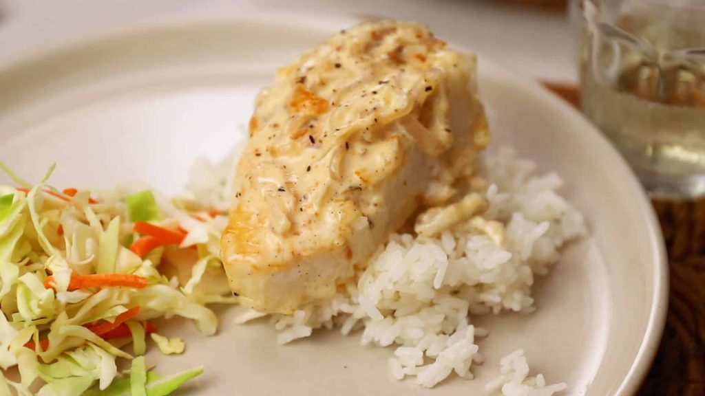mahi with vanilla shallot cream on some jasmine rice with shredded veggies (cabbage and carrots) as side. All this food lays on a tan colored glass plate.