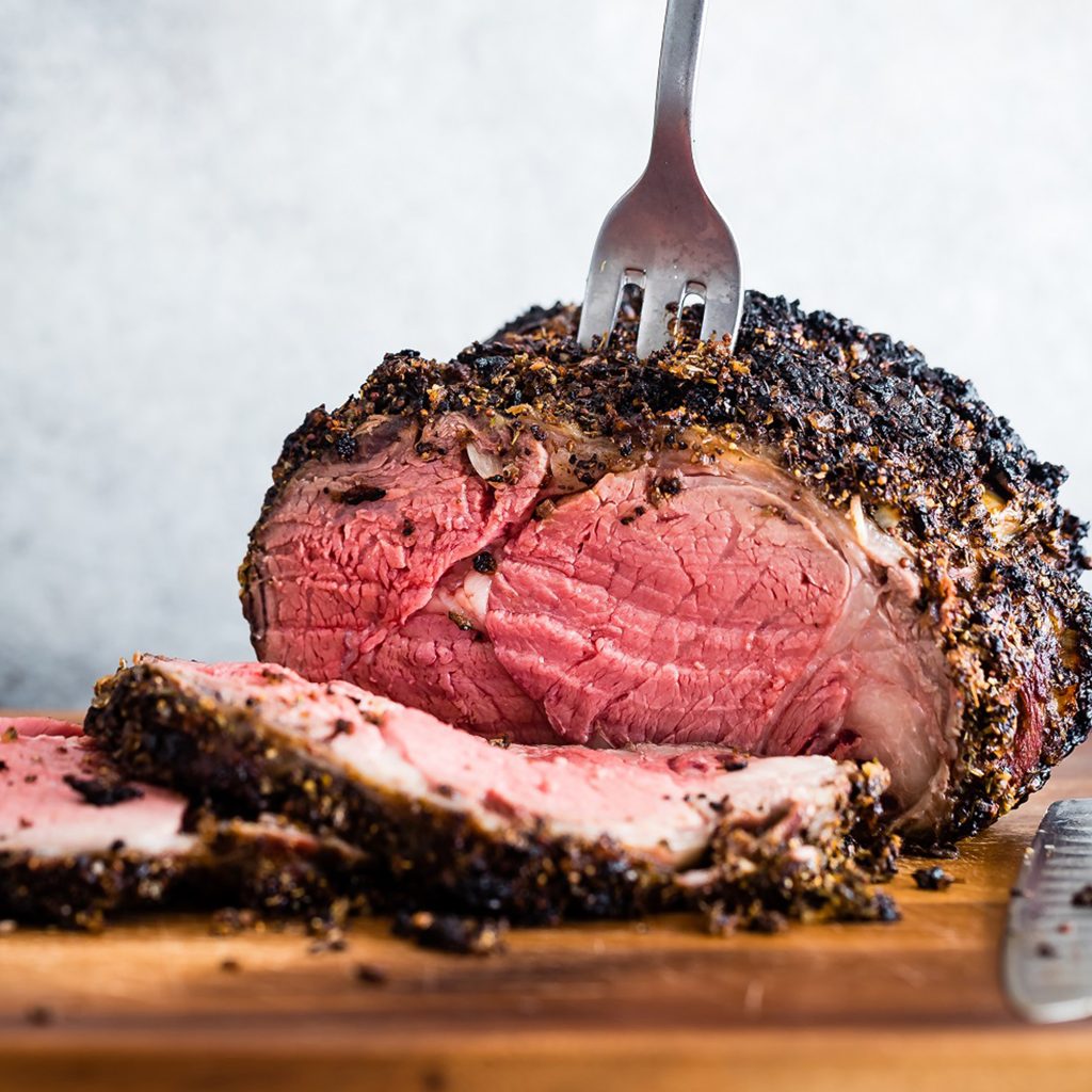 photo of a delicious prime rib sliced on a cutting board with a fork stabbed into it