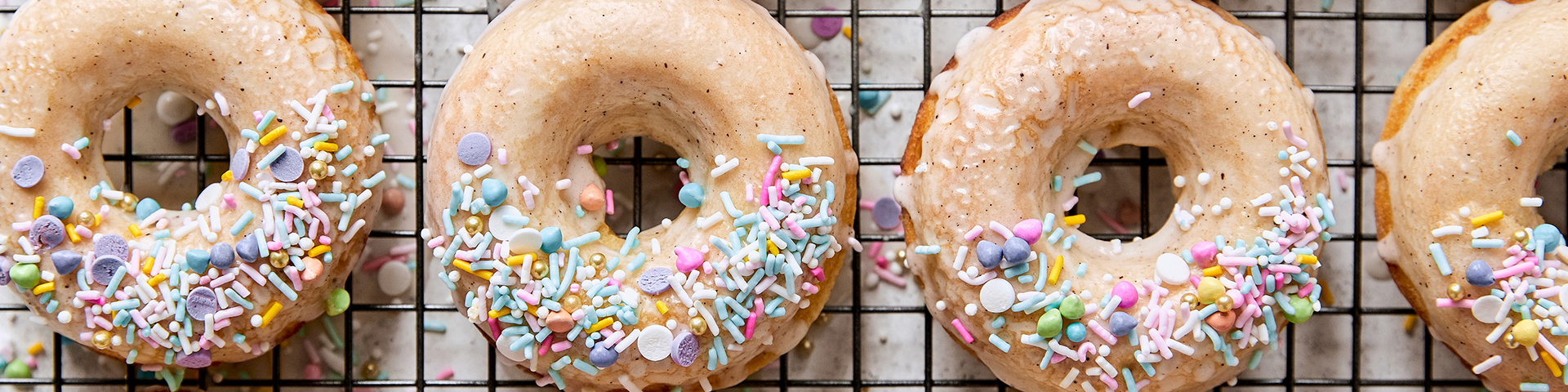 top view of vanilla bean donuts on cooling rack that have been glazed on top with sprinkles