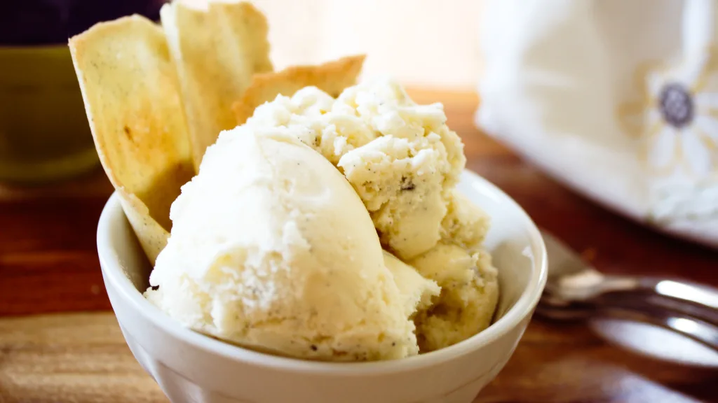 vanilla bean ice cream in a white bowl with homemade cone sticking out of the ice cream.