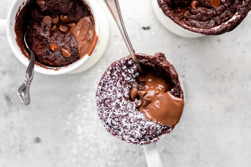 3 mugs of cake with a spoon on neutral background