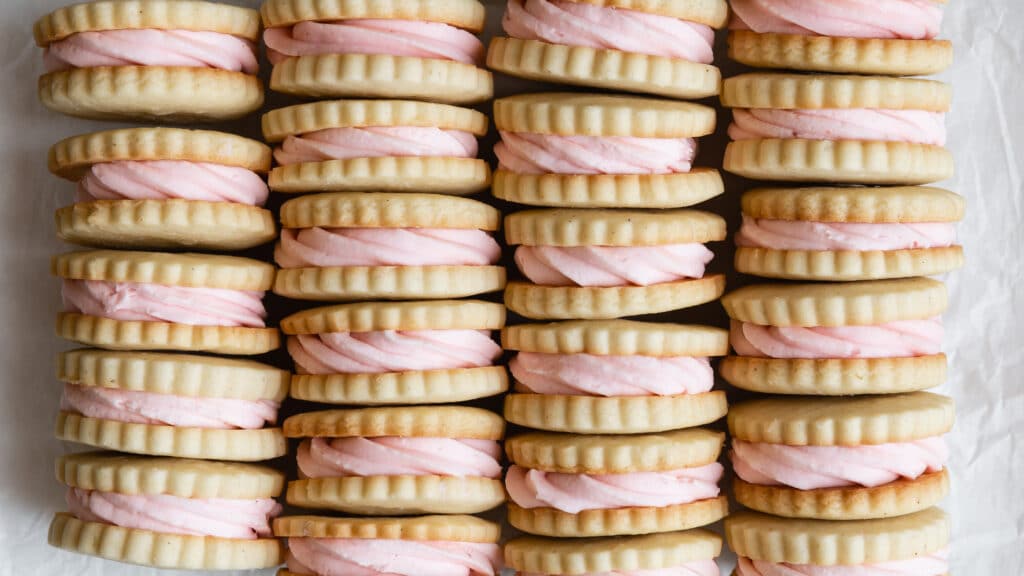 Vanilla Bean Sandwich Cookies with Strawberry Buttercream Filling Stacked in Four Rows