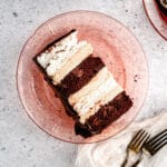 Slice of angel food and chocolate cake with peanut butter mousse on pink plate and grey background