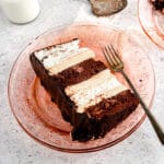 Slice of angel food and chocolate cake with peanut butter mousse on pink plate and grey background