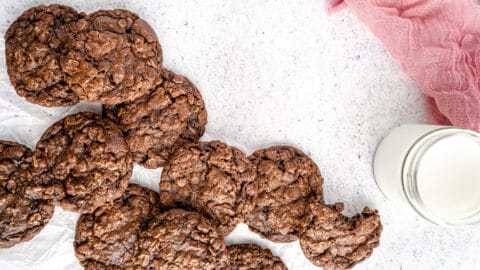 Double Chocolate Oatmeal Cookies overhead on white parchment paper with milk