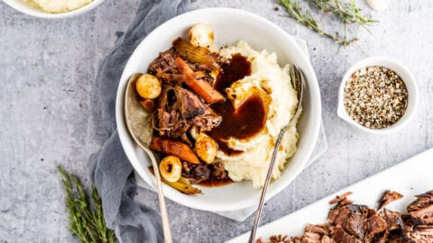 Pot roast sliced in bowl with gravy and mashed potatoes