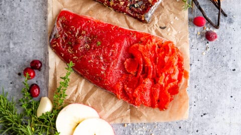 Cured Salmon Gravlax on cutting board with fresh herbs