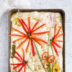 Foccacia bread with fresh vegetables and herbes about to be baked in a pan