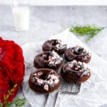 Chocolate donuts with chocolate glaze and crushed peppermint candies on cooling rack