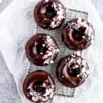 Chocolate donuts with chocolate glaze and crushed peppermint candies on cooling rack