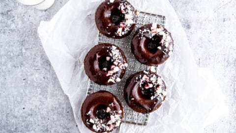 Chocolate donuts with chocolate glaze and crushed peppermint candies on cooling rack
