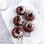 Chocolate donuts with chocolate glaze and crushed peppermint candies on cooling rack