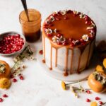 Brownie layer cake with caramel drip and seasonal fall fruits on a neutral background