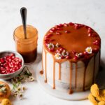 Brownie layer cake with caramel drip and seasonal fall fruits on a neutral background