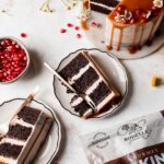 Slices of Brownie layer cake with caramel drip and seasonal fall fruits on a neutral background