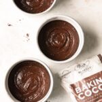 Brownie layer cake batter in pans on a neutral background
