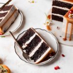 Slices of Brownie layer cake with caramel drip and seasonal fall fruits on a neutral background