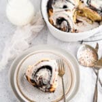 One chocolate cinnamon roll on a plate with silverware and milk