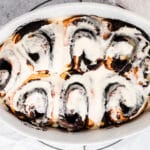 chocolate cinnamon rolls with white frosting in baking dish
