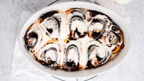 chocolate cinnamon rolls with white frosting in baking dish