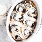 chocolate cinnamon rolls with white frosting in baking dish