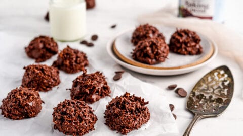Chocolate macaroon cookies on neutral background shown with plate, milk, and serving tools