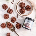 Chocolate macaroon cookies on neutral background shown with plate, milk, serving tools and Rodelle Baking cocoa