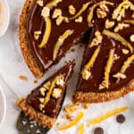 Flourless walnut cake with chocolate glaze on a neutral background with slice being taken out