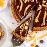 Flourless walnut cake with chocolate glaze on a neutral background with slice being taken out
