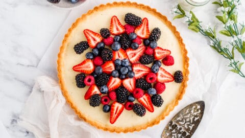 Overhead shot of Vanilla custard tart with berries on neutral background