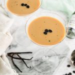 Vanilla espresso martini in martini glass with vanilla beans and marble background