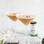 Vanilla espresso martini in martini glass with vanilla beans and marble background