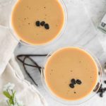 Vanilla espresso martini in martini glass with vanilla beans and marble background