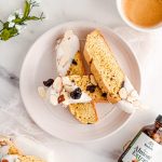 Almond Cherry Biscotti dipped in white chocolate on white plate on top of marble background