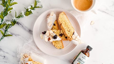 Almond Cherry Biscotti dipped in white chocolate on white plate on top of marble background