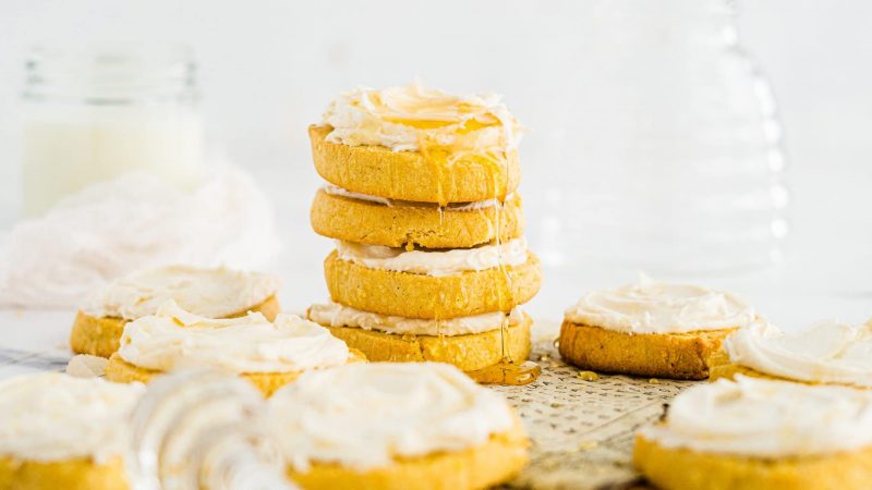 Cornbread cookies with honey frosting stacked on a neutral background
