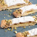 Puffy vanilla danish with vanilla glaze and pistachios on a slab of marble
