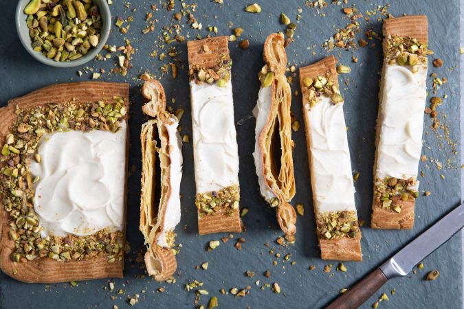 Puffy vanilla danish with vanilla glaze and pistachios on a slab of marble