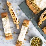 Puffy vanilla danish with vanilla glaze and pistachios on a slab of marble