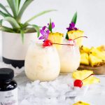 Two Pina Colada cocktails with tropical fruit, cherries and ice