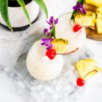 Two Pina Colada cocktails with tropical fruit, cherries and ice