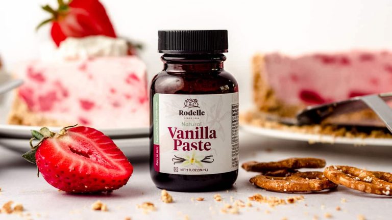 Rodelle vanilla paste in front of Creamy Strawberry Pie with crumbly crust topped with strawberry and whipped cream on a white plate