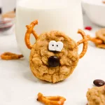close up side profile of a oatmeal cream pie reindeer leaning agains a glass of milk.