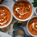 bowls of orange pumpkin soup on wooden background
