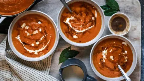 bowls of orange pumpkin soup on wooden background