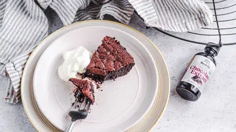 Fudge chocolate skillet cake on neutral background with bite taken out.