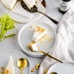 Vegan Vanilla Cheesecake - sliced with garnish of crumbled cookies on white plates with silver spoons
